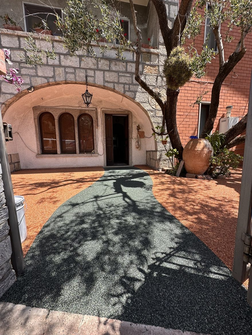 Cortile privato nel Cilento con pavimentazione drenante in resina bicolore, camminamento verde e fondo color cotto, posata da Edil Lenza sul pavimento esistente